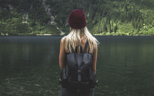 Rear view of backpack woman standing by lake