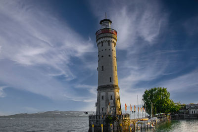 Lighthouse by sea against sky