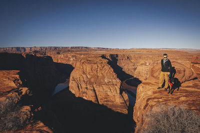 A man with a dog is standing near horseshoe bend, arizona