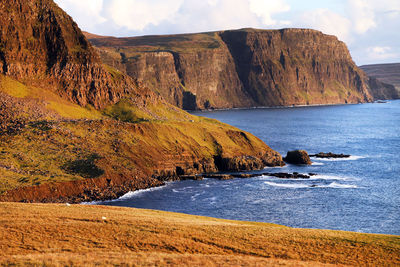 Scenic view of sea by mountains against sky