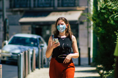 Young woman wearing sunglasses standing on street in city