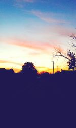 Silhouette trees on landscape against sky at sunset