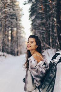 Portrait of young woman in snow at forest