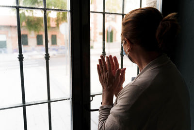 Side view of woman looking through window