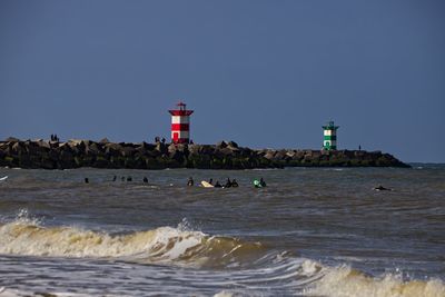 Lighthouse by sea against clear sky