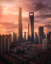 Modern buildings in city against cloudy sky during sunset