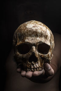 Close-up of human hand holding skull