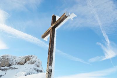 Low angle view of snow covered cross against sky