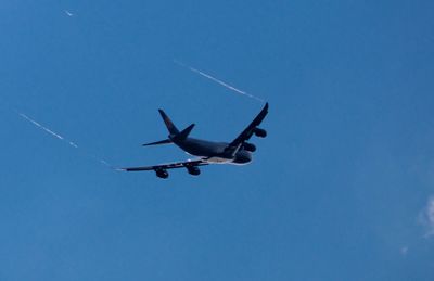 Low angle view of airplane flying against clear blue sky