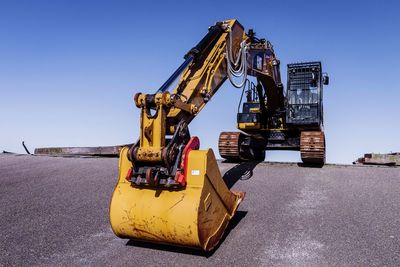 Excavator on road against blue sky