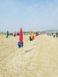 Tied umbrellas at beach in deauville against sky