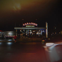 Illuminated road sign on street in city at night