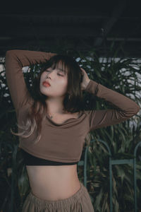 Portrait of young woman standing against plants