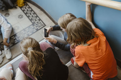 High angle view of male and female friends sitting on staircase of school building