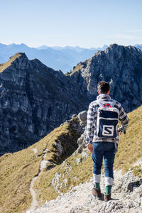 Rear view of man standing on mountain against sky