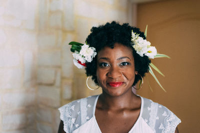 Portrait of woman wearing flowers while standing by wall