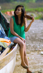 Full length portrait of young woman sitting on boat at beach