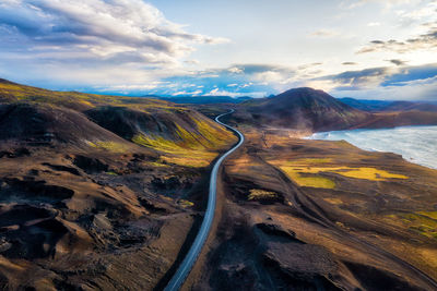 Scenic view of road by mountains against sky