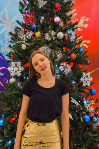 Young woman standing against christmas tree