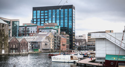 Buildings by river against sky in city