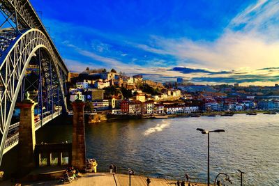 Illuminated buildings by river against sky in city
