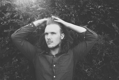 Young man with hand hair standing by plants