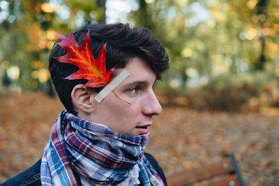 Side view of man with leaf stuck on face looking away