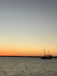 Silhouette sailboats in sea against clear sky during sunset