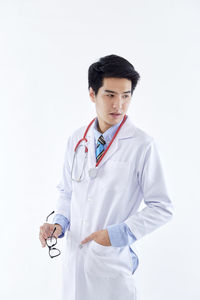 Young man looking away while standing against white background