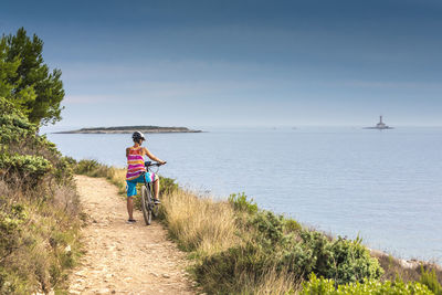 Woman with bicycle at beach against sky