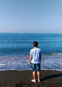 Rear view of man standing in front of sea