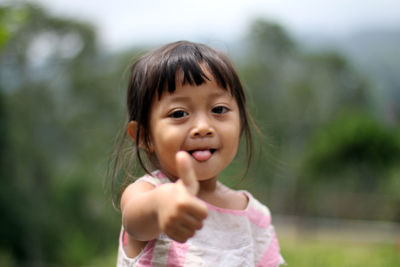 Portrait of cute girl showing thumbs up