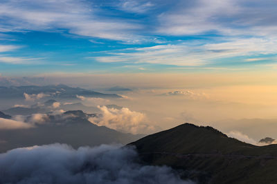 Aerial view of clouds covering volcanic landscape against sky during sunset