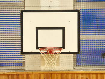 Basketball hoop in the high school gym. safety nets over windows. iluminated by fluorescent lighting