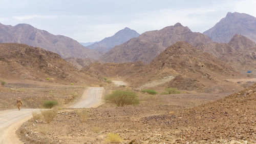 Scenic view of road by mountains against sky