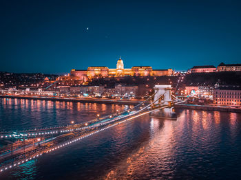 Illuminated bridge over river in city at night