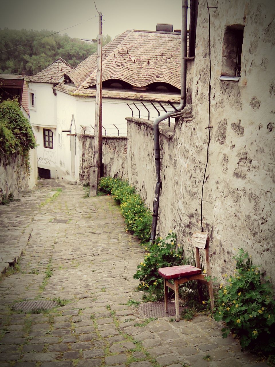 architecture, built structure, building exterior, house, empty, the way forward, absence, residential structure, wall - building feature, sunlight, walkway, wall, narrow, residential building, day, chair, cobblestone, no people, outdoors, footpath