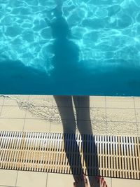 Low section of woman standing by swimming pool