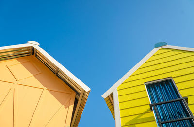 Low angle view of yellow building against clear blue sky