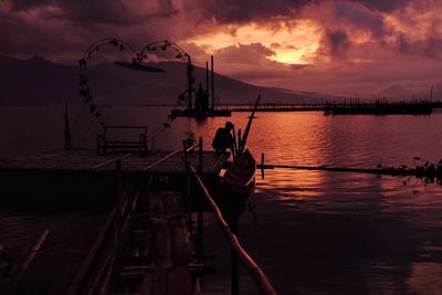 Silhouette man by lake during sunset