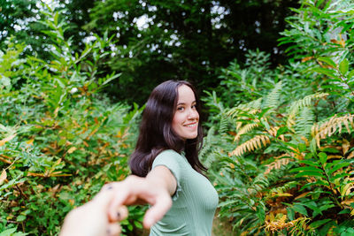 Portrait of smiling woman standing against plants