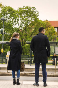 Rear view of man and woman standing at tram station