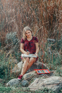 Portrait of smiling young woman sitting on land