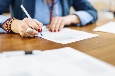 Crop stylish woman writing on paper document