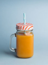 A jar of peach juice on blue background