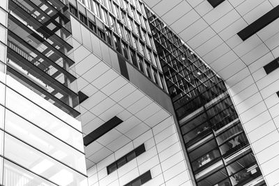 Low angle view of modern glass building in city against sky