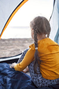 Rear view of woman sitting against sea