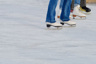 Low section of people ice-skating on ice rink during winter