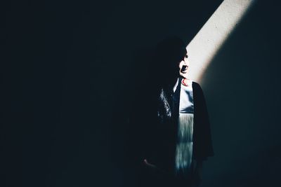 Sunlight falling on woman against wall