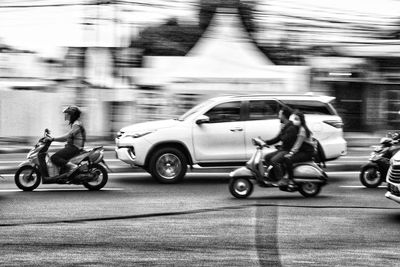 Side view of man riding motor scooter on street